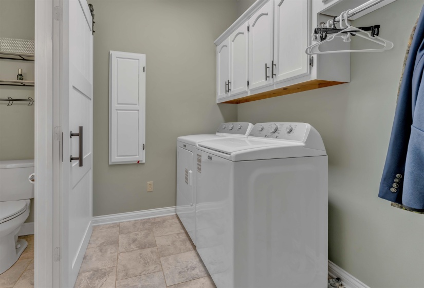 Laundry area featuring a top-load washer and dryer, upper cabinetry with dark hardware, and a hanging rod