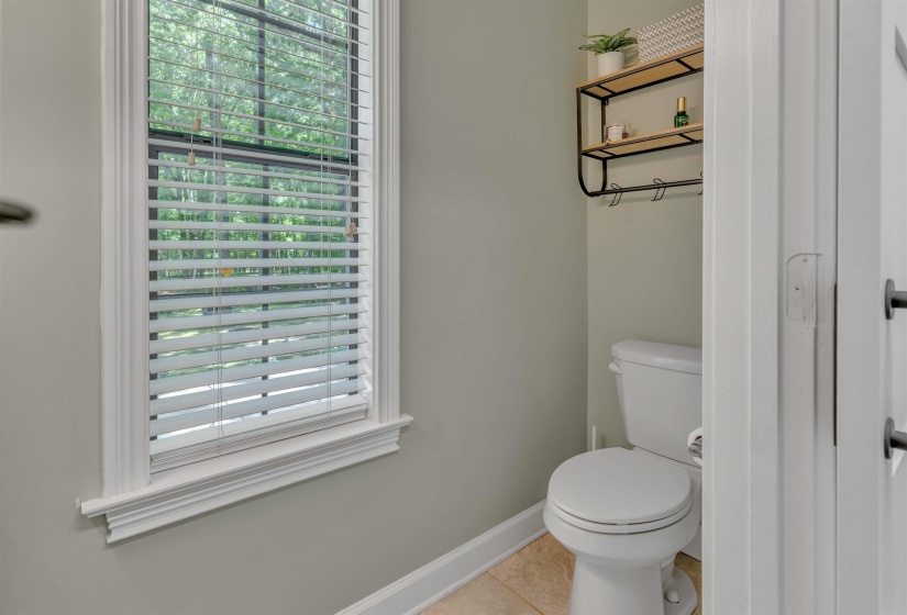 Powder room featuring a window with white blinds, neutral wall paint, and ceramic tile flooring