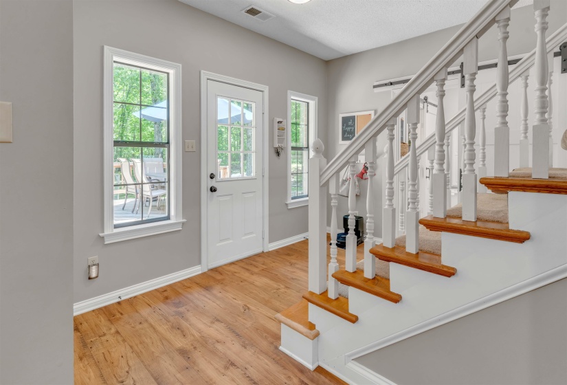 Entryway featuring wood-finish flooring, a white paneled door with glass inserts, and multiple windows