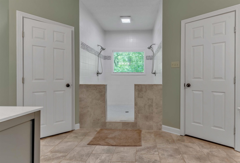 Walk-in shower with dual shower heads, white subway tile, and a decorative tile accent