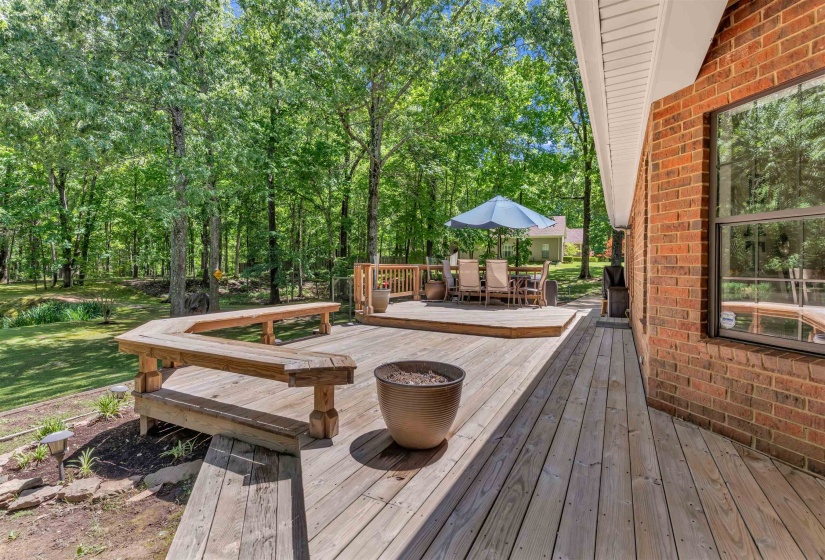 Expansive multi-level wood deck featuring built-in bench seating and a brick exterior