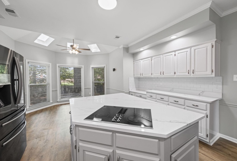 Kitchen with backsplash, stainless steel fridge with ice dispenser, white cabinets, dark wood finished floors, and light stone countertops