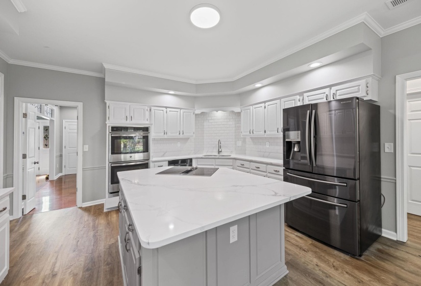 Kitchen featuring crown molding, stainless steel appliances, white cabinetry, tasteful backsplash, and dark wood-style flooring