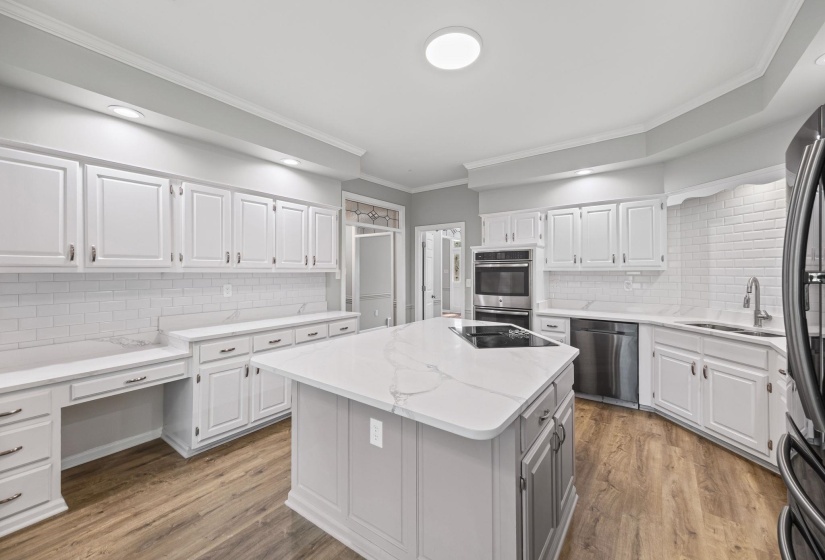 Kitchen with crown molding, white cabinetry, tasteful backsplash, light wood-style flooring, and light stone countertops