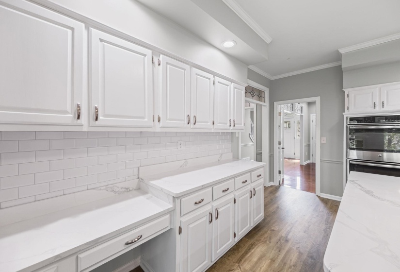 Kitchen featuring tasteful backsplash, ornamental molding, light stone countertops, dark wood finished floors, and white cabinetry