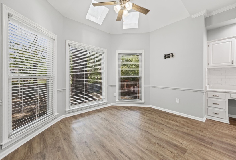 Unfurnished dining area with light wood-style floors, a skylight, ceiling fan, and built in desk