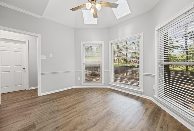 Unfurnished room with a skylight, wood finished floors, and ceiling fan
