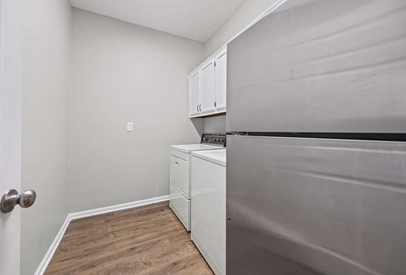 Laundry area featuring dark wood finished floors, cabinet space, and washer and clothes dryer