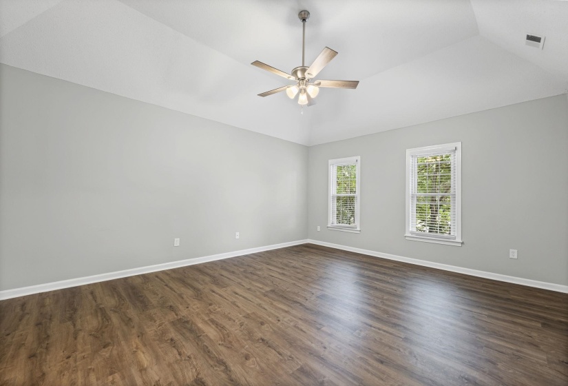 Spare room featuring dark wood finished floors, lofted ceiling, and a ceiling fan