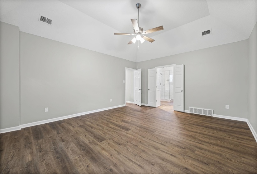 Unfurnished bedroom featuring dark wood-style floors, ceiling fan, lofted ceiling, and connected bathroom