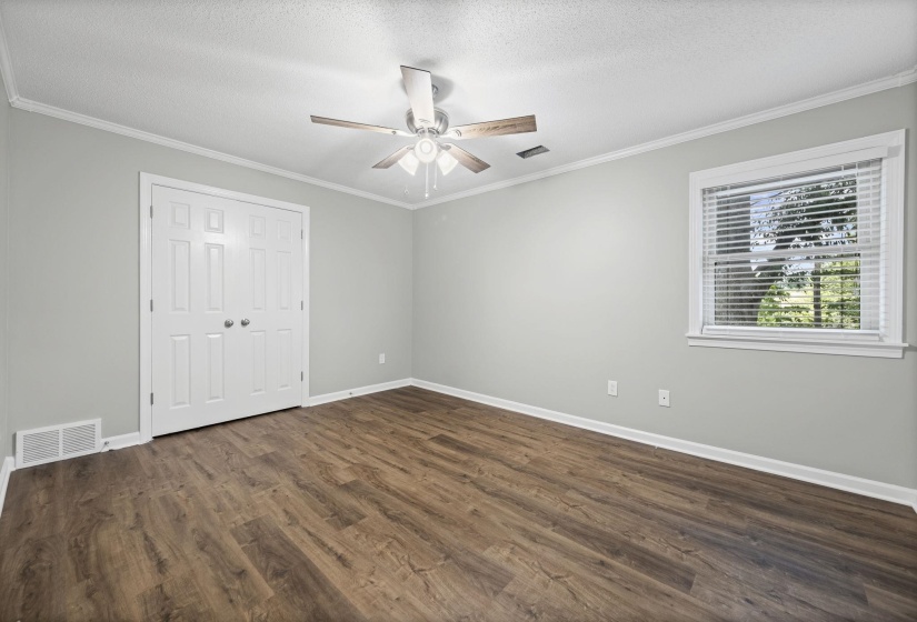 Unfurnished bedroom with crown molding, dark wood finished floors, a textured ceiling, a ceiling fan, and a closet