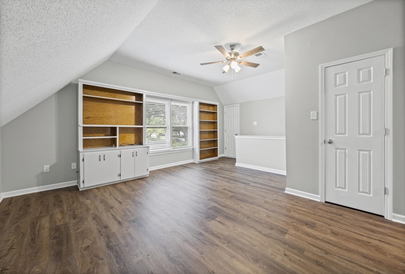 Unfurnished living room with a textured ceiling, dark wood-type flooring, ceiling fan, and lofted ceiling