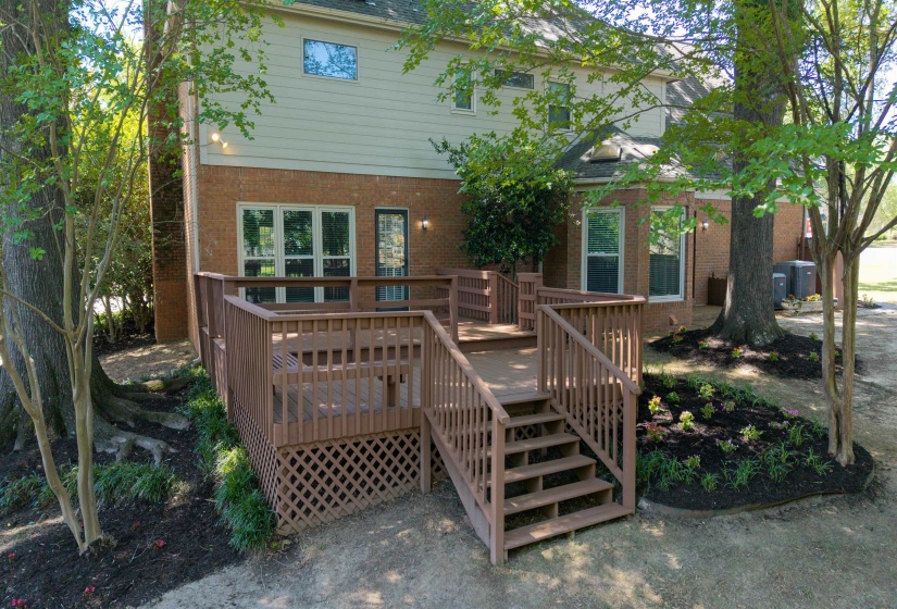 Multi-level wood deck with lattice skirting, brick exterior, and landscaped beds