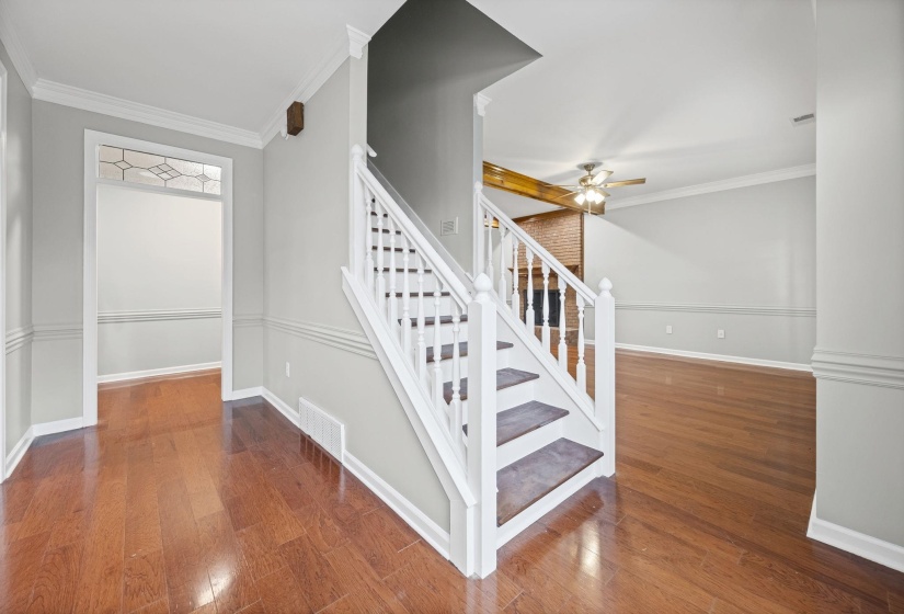 Stairway with crown molding, wood finished floors, and a ceiling fan