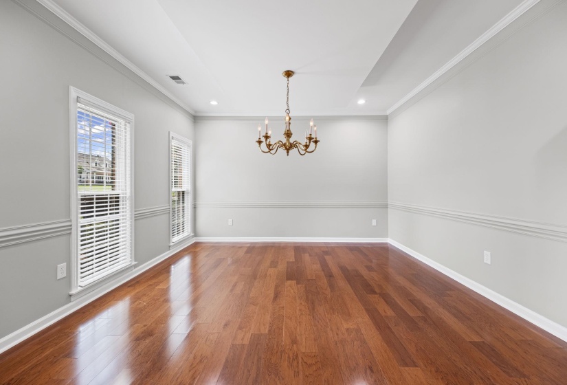 Unfurnished dining area featuring ornamental molding, dark wood-style flooring, a chandelier, and recessed lighting