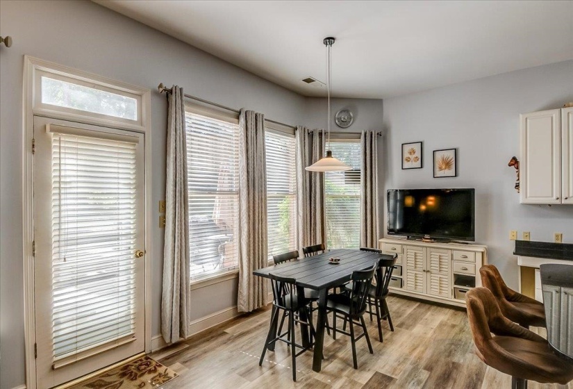 Breakfast area featuring wood-finish flooring, a pendant light fixture, and multiple windows with blinds