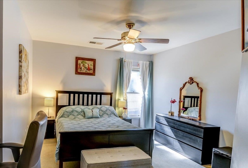 Neutral-toned bedroom with a ceiling fan light fixture and recessed lighting