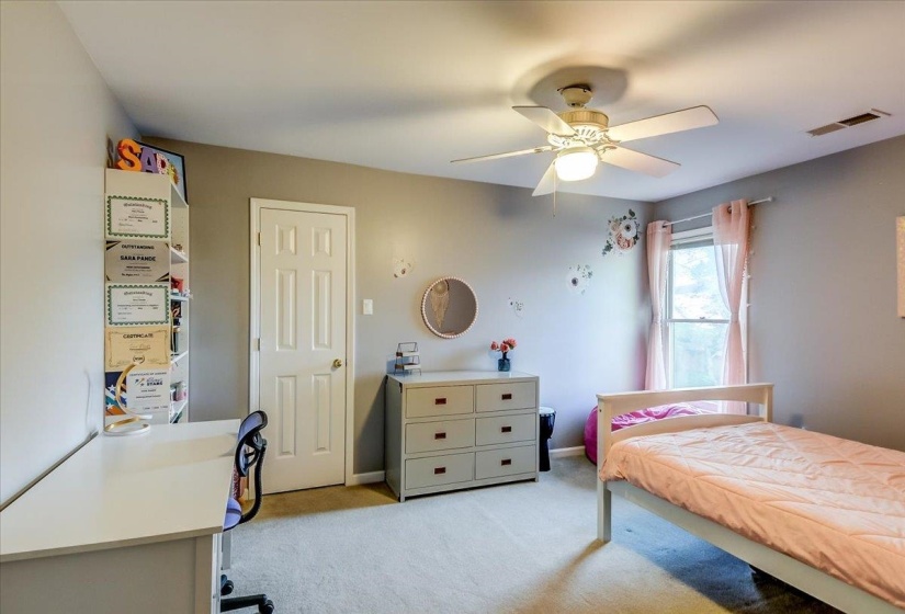 Carpeted room featuring a ceiling fan with integrated lighting, a single window with curtain rods, and a white paneled door