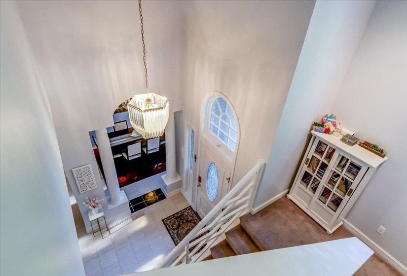 Soaring entryway featuring a contemporary chandelier and a paneled front door with an arched transom