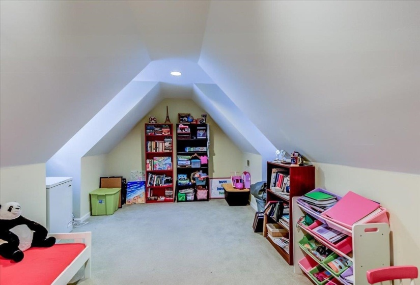 Carpeted attic space with sloped ceilings and recessed lighting