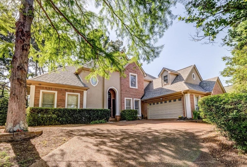 Brick and stucco exterior featuring multiple gables, an arched entryway, and dormer windows