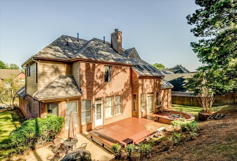 Brick and siding exterior featuring a multi-level deck, a stone-lined fire pit, and ample yard space