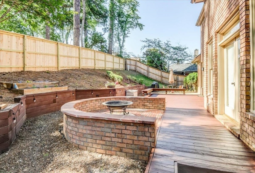 Expansive exterior featuring a wood-finish deck, brick exterior, and a built-in brick fire pit
