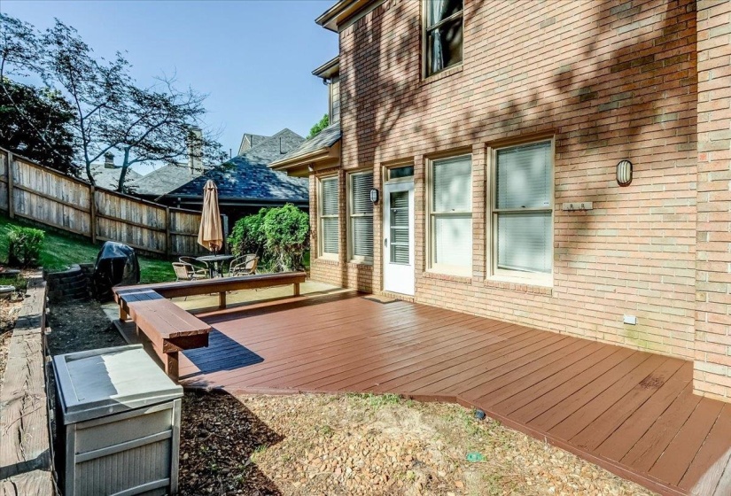 Expansive deck featuring a wood-finish surface, integrated bench seating, and direct access to the interior via a glass-paneled door