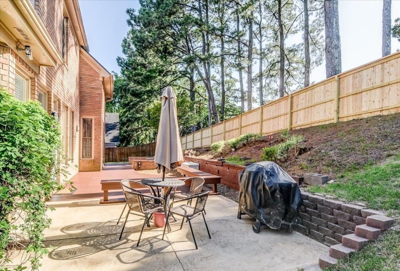 Outdoor living area featuring a concrete patio, a multi-level wood deck, a wood privacy fence, and a brick retaining wall