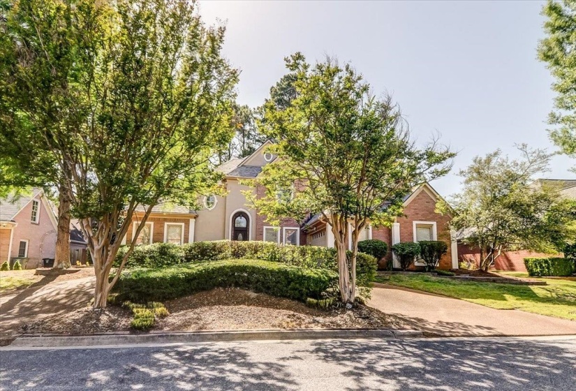 Traditional-style home featuring a brick and stucco facade, an arched entry door, and a circular window