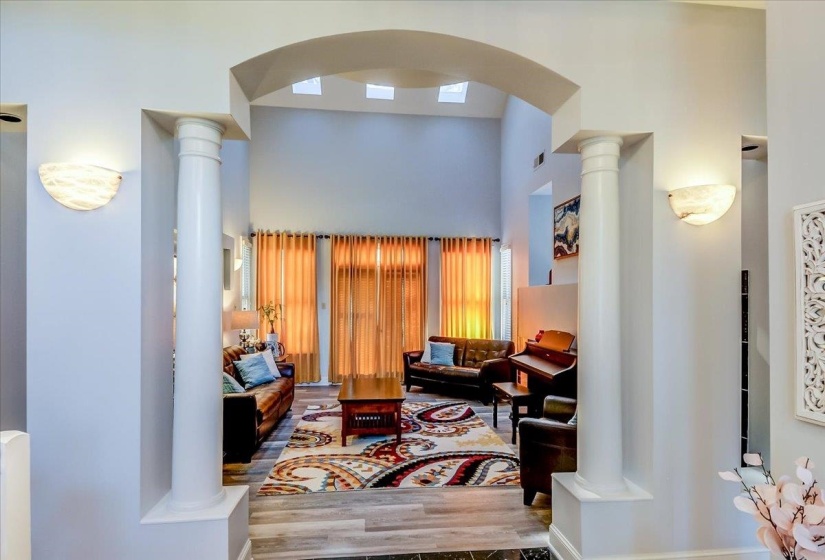 Archway entry featuring decorative columns and sconce lighting