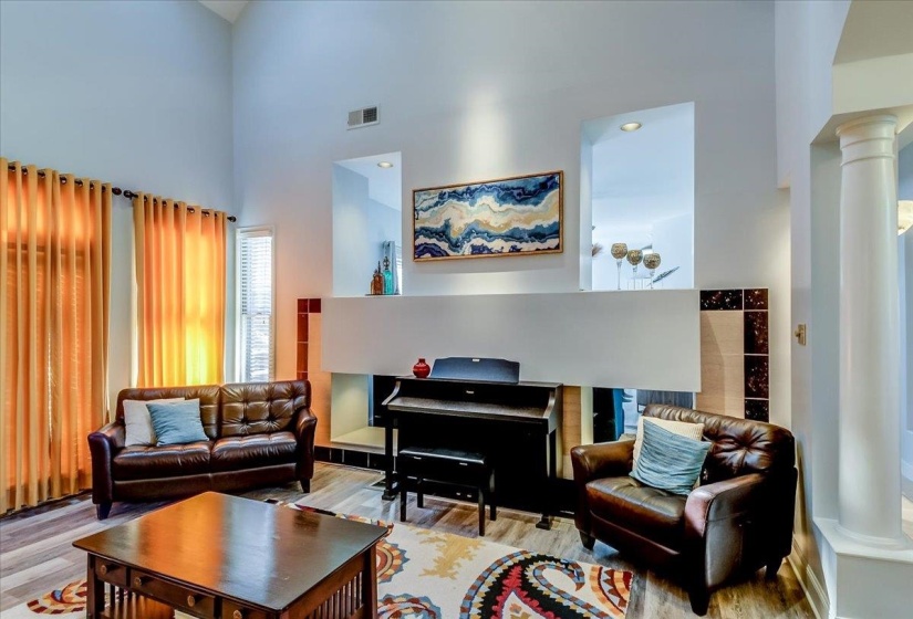 Vaulted ceiling living area featuring wood-finish flooring, a decorative wall niche, and an architectural column
