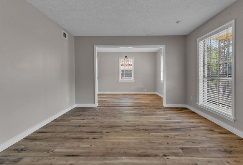 Open concept interior featuring wide plank wood-finish flooring, neutral wall tones, white trim, and a decorative chandelier