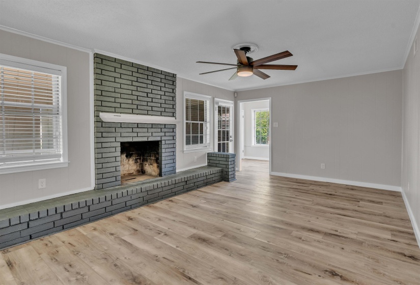 Living space featuring wood-finish flooring and a painted brick fireplace with hearth