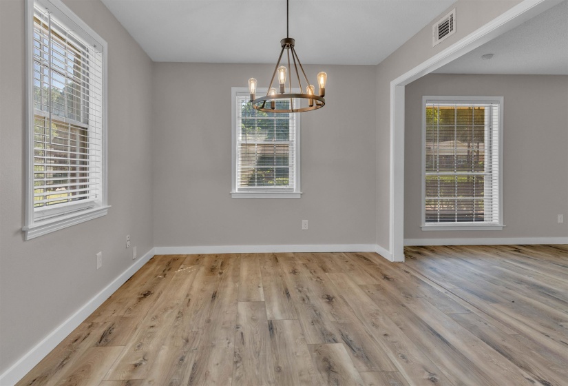 Spacious room featuring wood-finish flooring, light grey wall paint, and multiple windows with blinds