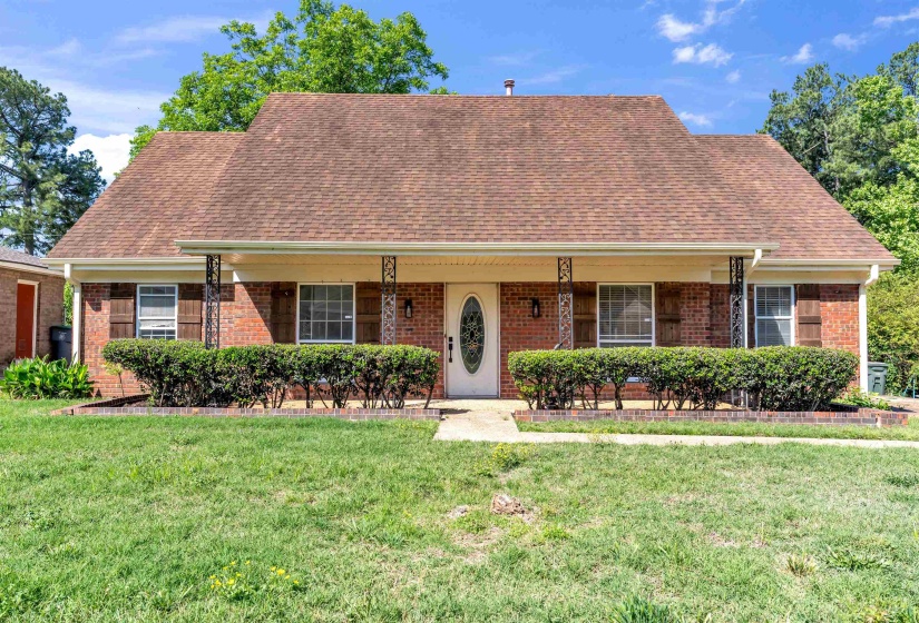 Brick exterior with a prominent front porch, decorative metal columns, a single entry door with an oval glass insert, and a gabled roof