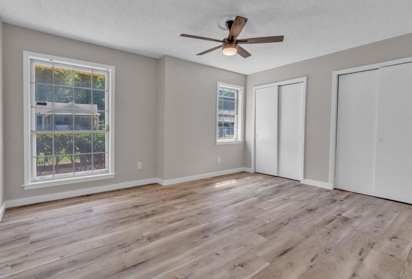 Spacious room featuring wood-finish flooring, light grey walls, and white trim