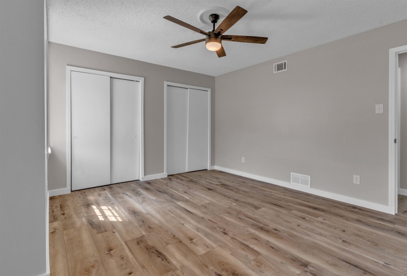 Spacious room featuring wood-finish flooring and a ceiling fan with integrated lighting