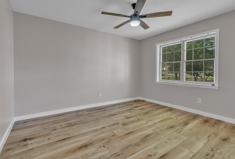 Interior room featuring wood-finish flooring, light gray walls, white trim, and a window with white grilles