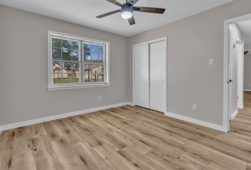 Spacious room featuring wood-finish flooring, light gray wall paint, and white baseboards