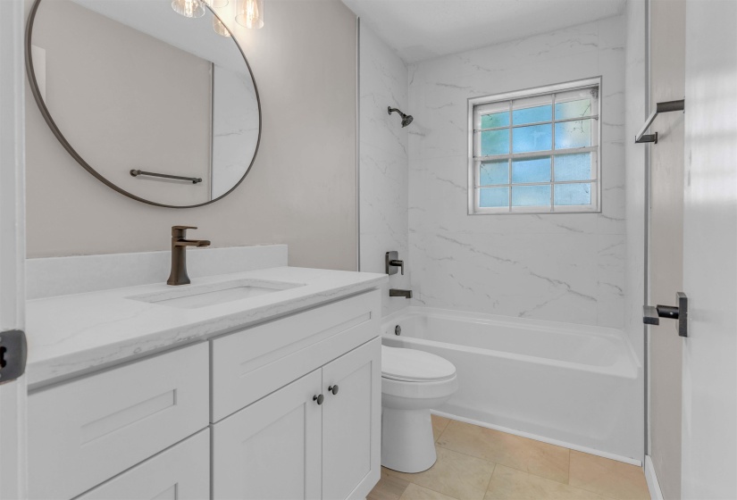 Modern bathroom featuring a white vanity with an integrated sink and bronze-finish hardware