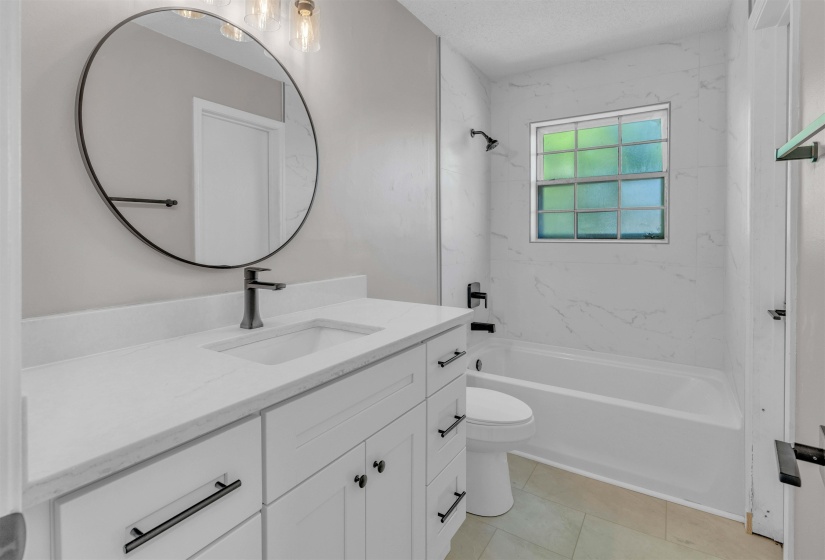 Modern bathroom featuring a white vanity with an integrated sink, matte black faucet, and coordinating hardware