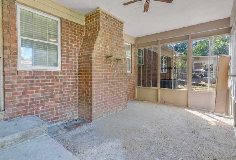 Screened-in porch featuring a brick exterior wall, a built-in brick chimney structure, and a ceiling fan
