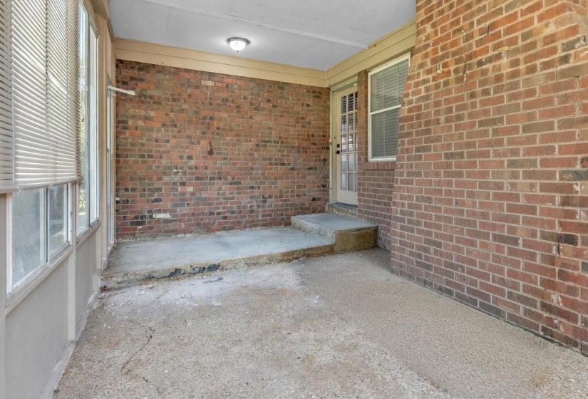 Enclosed porch with brick wall accent and concrete flooring