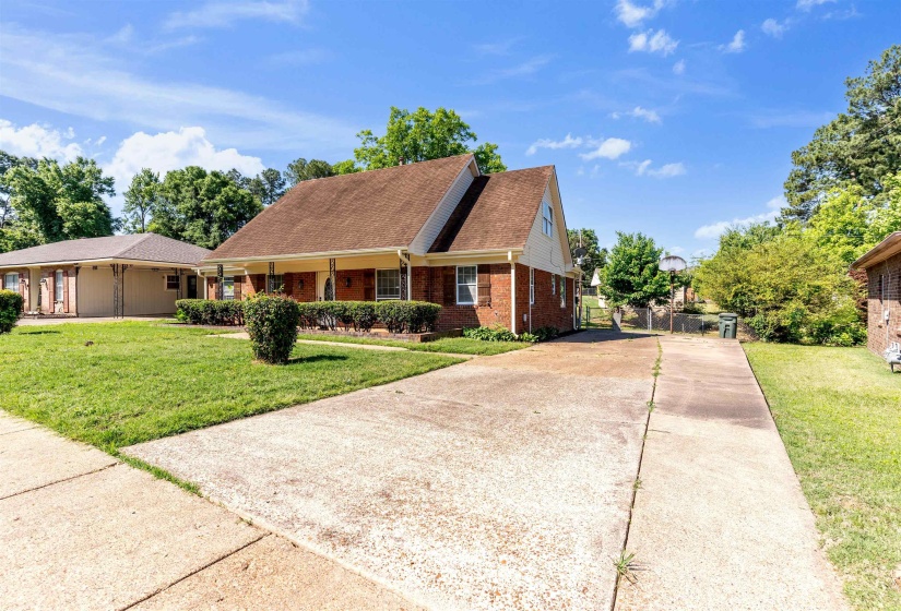Brick exterior residence featuring a covered front porch with column supports, a gabled roofline, and an extended concrete driveway