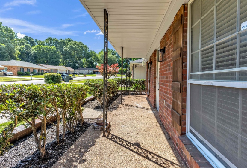 Covered front porch featuring a brick facade, white soffit, and decorative iron support columns