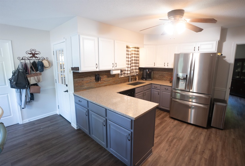 Kitchen featuring wood-finish flooring, two-tone cabinetry with white upper and gray lower cabinets, light-toned countertops, and a full stainless steel appliance suite