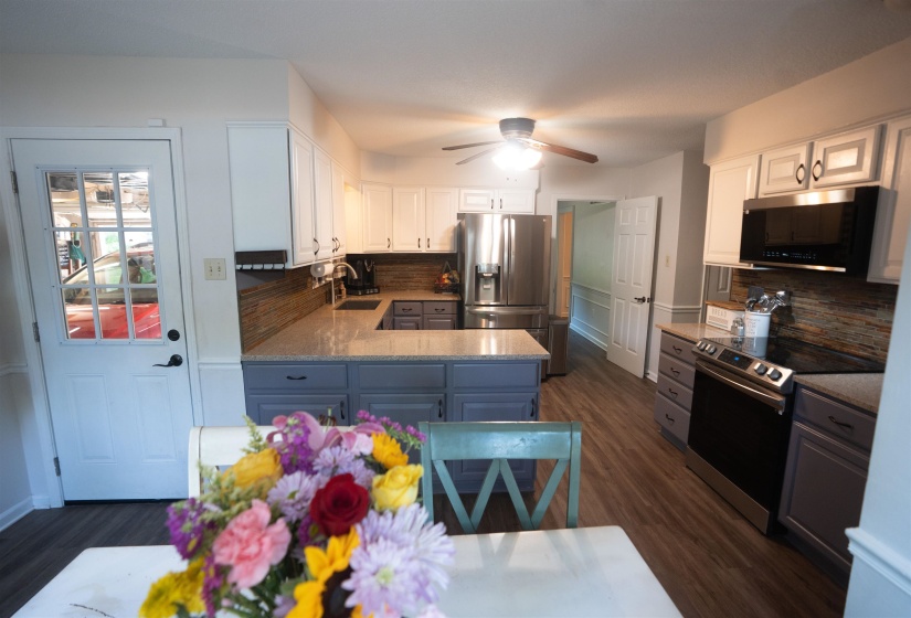 Kitchen featuring wood-finish flooring, two-tone cabinetry with white upper and gray lower cabinets, stainless steel appliances, and light-toned countertops