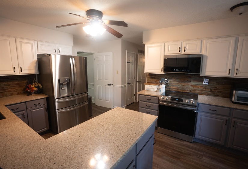 Kitchen featuring two-tone cabinetry with white upper cabinets and gray lower cabinets, light-toned countertops, and a full suite of stainless steel appliances