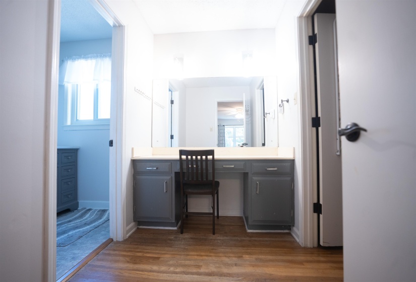 Vanity area featuring wood-finish flooring, gray base cabinetry, light-toned countertop, and an integrated mirror